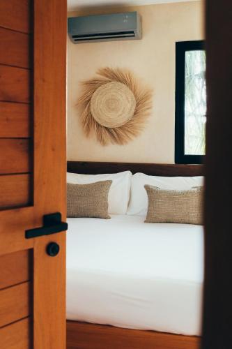 a bedroom with a bed with white sheets and a window at Cucu Hotel El Cuyo in El Cuyo