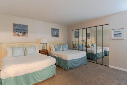 a bedroom with two beds and a mirror at Seascape 315 - Oceanfront Condo Overlooking Pool in Isle of Palms