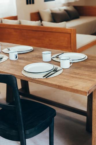 a wooden table with plates and utensils on it at Cucu Hotel El Cuyo in El Cuyo