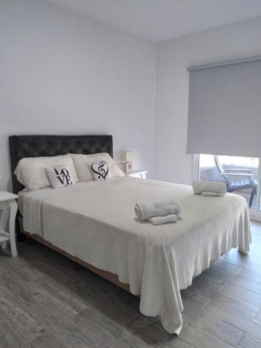 Un dormitorio blanco con una cama grande con toallas. en MIRADORES DEL BOULEVAR en Tigre