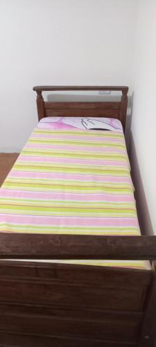 - un lit avec un cadre en bois et un matelas rayé dans l'établissement Hilda Roga, à Posadas