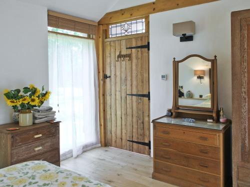 サックスマンダムにあるThe Coach Houseの鏡と木製ドレッサー付きのベッドルーム