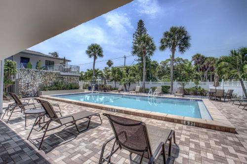 a swimming pool with chairs and a table and a pool at Siesta Sands Beach Resort Gulf View in Sarasota