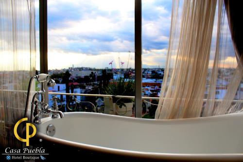 a bath tub in front of a window with a view at Hotel Temático Casa Puebla in Puebla