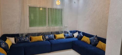 a blue couch with yellow pillows in a living room at Bel appartement quartier Marjane in Meknès