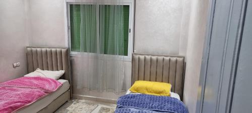 a small room with two beds and a window at Bel appartement quartier Marjane in Meknès