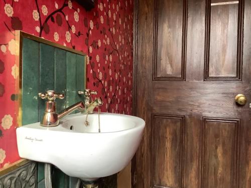 a bathroom with a white sink and a wooden door at Rooms or Entire City House 6min drive to Stadium of Light in Sunderland