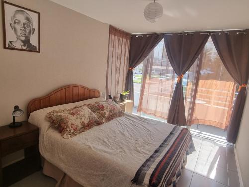 a bedroom with a bed and a large window at Hermoso departamento, cómodo y tranquilo, cerca de todo, a pasos de la playa in Iquique