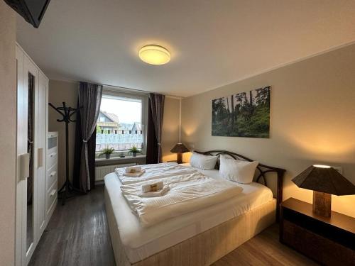 a bedroom with a large white bed with a window at Wurmbergblick Nico in Braunlage 4 Sterne zertifiziert vom DTV inklusive Wäschepakete in Braunlage