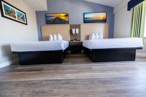 two beds in a hotel room with wood floors at Days Inn by Wyndham Monterey Downtown in Monterey