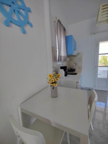 a white dining room table with a vase of flowers on it at Kleanthi Apartments in Drios