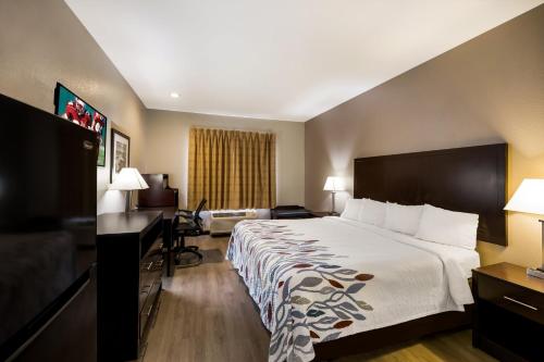 a hotel room with a large bed and a desk at Red Roof Inn Pecos in Pecos