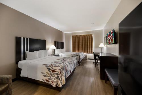 ein Hotelzimmer mit einem großen Bett und einem Schreibtisch in der Unterkunft Red Roof Inn Pecos in Pecos
