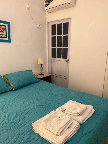 Un dormitorio con una cama verde con toallas. en Aires del Estero en Santiago del Estero