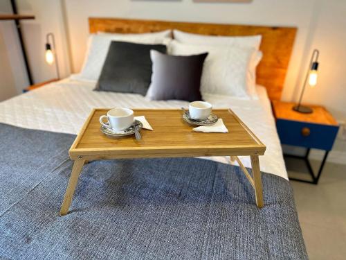 a wooden coffee table with two cups on top of a bed at Home Time Studios in Florianópolis