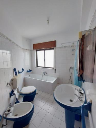 a bathroom with two toilets and a tub and a sink at Coluna Mar in Quarteira