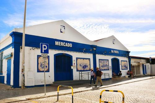 two people walking in front of a blue and white building at Coluna Mar in Quarteira