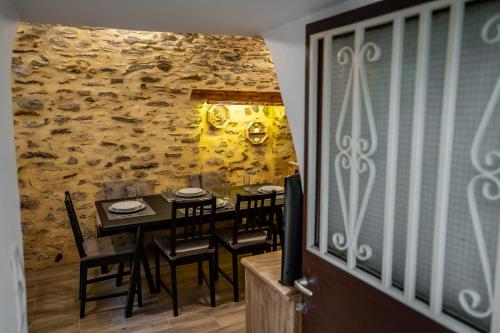 a dining room with a table and chairs and a stone wall at Sea & Mountain Serenity in Plátsa