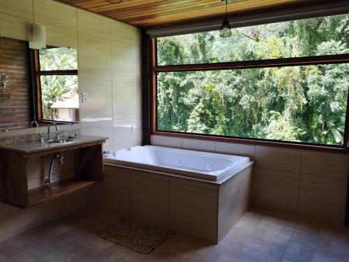 a large bathroom with a tub and a large window at Pousada Pizzaria do Vale in Visconde De Maua