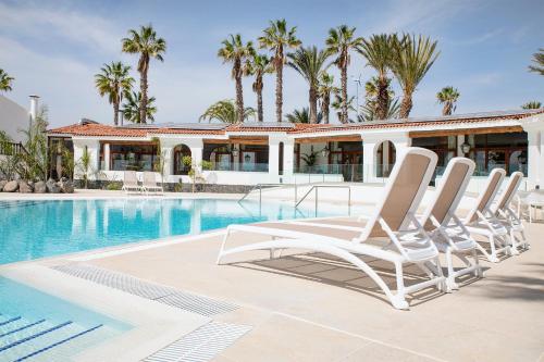 a group of lounge chairs next to a swimming pool at THE CLUB - Accommodation - Dining - Events in San Miguel de Abona