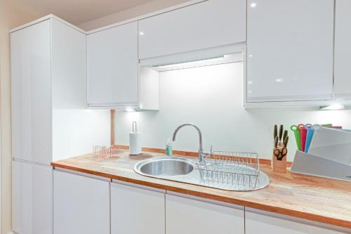a kitchen with white cabinets and a sink at Spacious Luxury 3 Bed Apt W Parking by 360Stays in Maidenhead