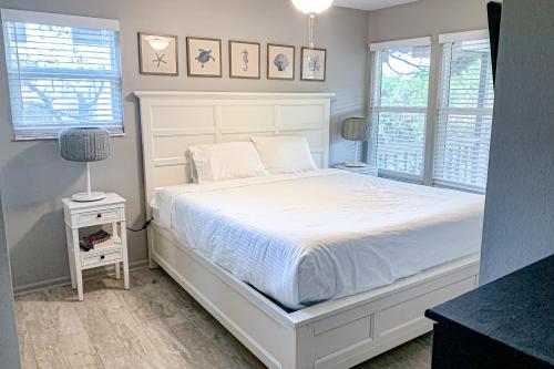 a bedroom with a white bed and two windows at Sea Pine Cottage in St. George Island