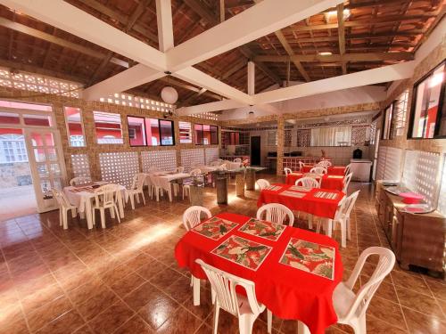 um restaurante com mesas vermelhas e cadeiras brancas em Villa Coelho - Pousada a 5 minutos de Guarajuba em Camaçari