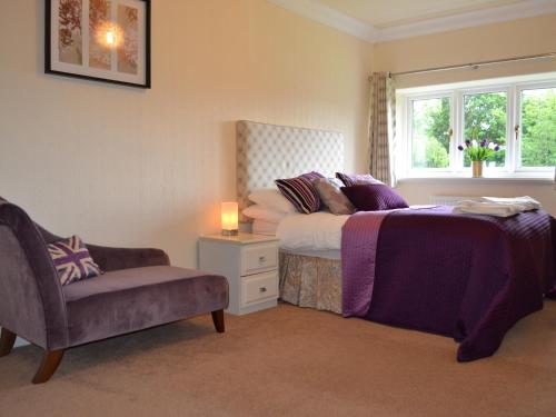 um quarto com uma cama, uma cadeira e uma janela em Meadowcroft No 7 em Bowness-on-Windermere