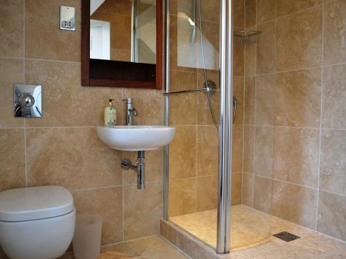 uma casa de banho com um chuveiro, um WC e um lavatório. em Meadowcroft No 7 em Bowness-on-Windermere