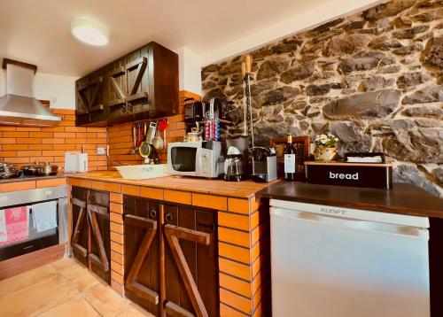 a kitchen with a counter and a stone wall at Typical House -Madeira Inn Group in Calheta