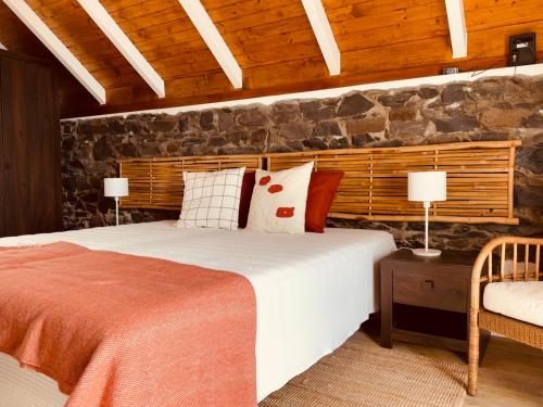 een slaapkamer met een bed en een stenen muur bij Madeira Inn The Typical House in Calheta