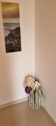 a vase with flowers in a corner of a wall at Apartmani S&S in Stara Novalja
