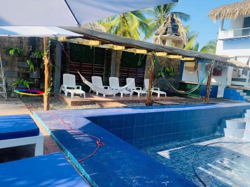 a swimming pool with white chairs and an umbrella at Casa Playa linda 28 in El Desengaño