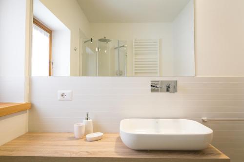 a white bathroom with a sink and a mirror at Mirtillo Blu Family Apartment in Alagna Valsesia