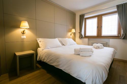 a bedroom with a white bed with towels on it at Mirtillo Blu Family Apartment in Alagna Valsesia
