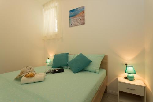 a bedroom with a bed with green sheets and two lamps at Apartments with a parking space Kastel Kambelovac, Kastela - 21071 in Kaštela