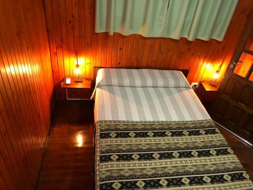1 dormitorio con 2 camas en una pared de madera en Hermosa y confortable cabaña en Puerto Iguazú