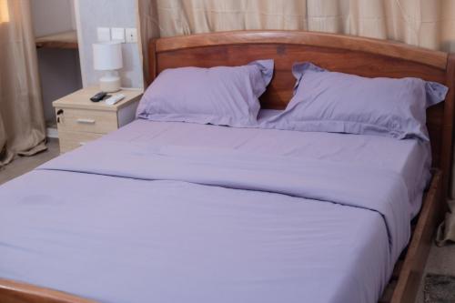 uma cama com lençóis brancos e uma cabeceira em madeira em Studio cosy et moderne em Lomé