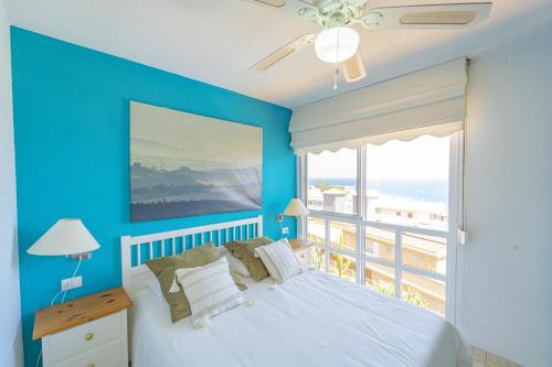 a blue bedroom with a bed and a large window at EDEN RENTALS Caletillas Ocean Views in Candelaria