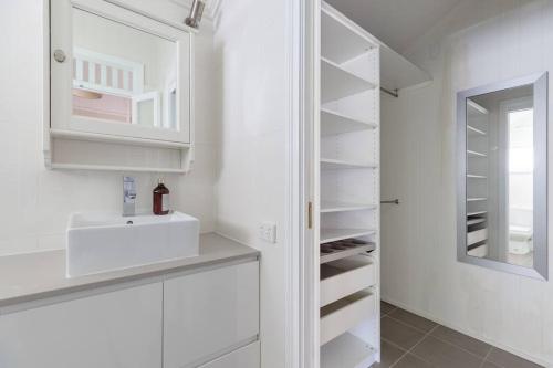 een witte keuken met een wastafel en een spiegel bij Quaint & Cosy 1 Bedroom Apartment in Queenslander. in Brisbane