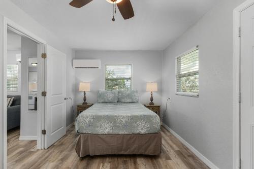 a white bedroom with a bed and two windows at Matlacha on Shoreview in Matlacha