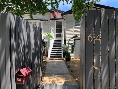 a white house with a fence and a gate at Charming 1920's 4Br freestanding Plantation Qldr. in Brisbane