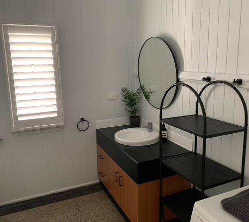 a bathroom with a sink and a mirror at Charming 1920's 4Br freestanding Plantation Qldr. in Brisbane