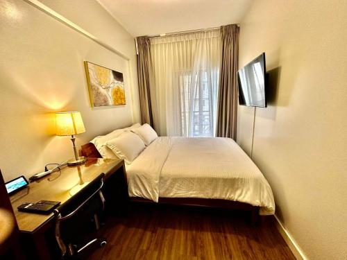 um quarto com uma cama e uma secretária com uma televisão em The Oak Smart Suite 2BR Baguio em Baguio