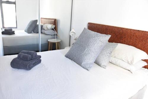 ein Schlafzimmer mit einem weißen Bett mit Kissen und einem Spiegel in der Unterkunft New Spacious 1 Bedroom Apartment Rosebery in Sydney