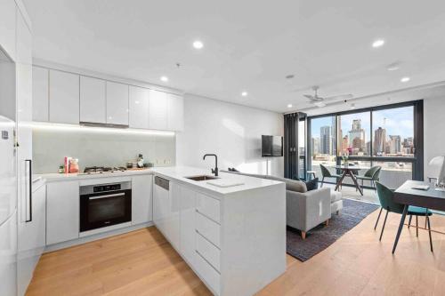 a kitchen with white cabinets and a living room at Fortitude Valley Prime position 2 x Bed, view, parking, pool in Brisbane