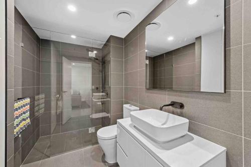 a bathroom with a sink and a toilet and a mirror at Prime position 1.5 BR w/ view/ parking / roof pool in Brisbane
