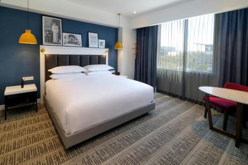 Un dormitorio con una gran cama blanca y una mesa en Culiacan Marriott Hotel, en Culiacán