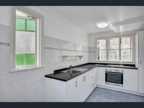 a white kitchen with a sink and two windows at Todd Street 72 in Townsville