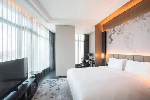 a bedroom with a large white bed and a large window at Sofitel Hangzhou Yingguan-Olympic Center Hotel in Hangzhou